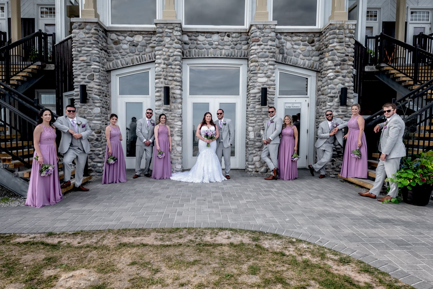 The bride and groom wedding party photos against the White Point main stone building in Nova Scotia.