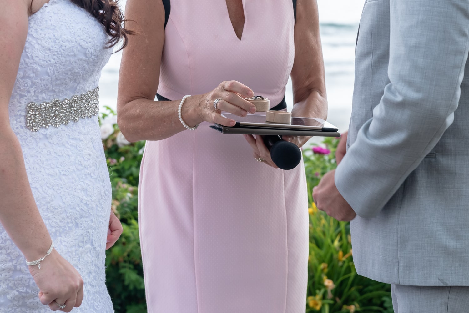 The wedding officiant holding the bride and groom's wedding rings at a White Point Beach Resort wedding.