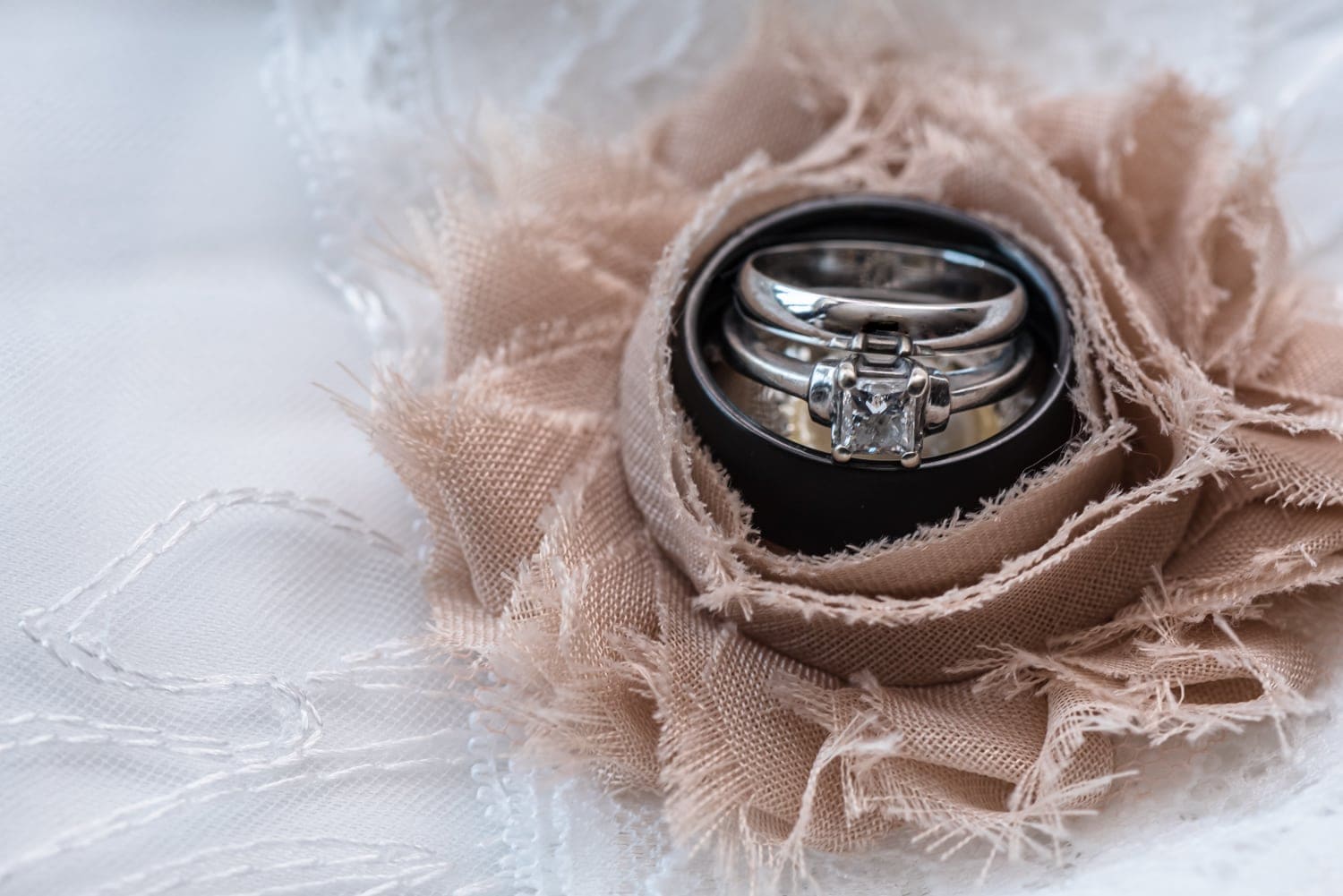 The wedding rings inside an ivory flower on the wedding garter belt.