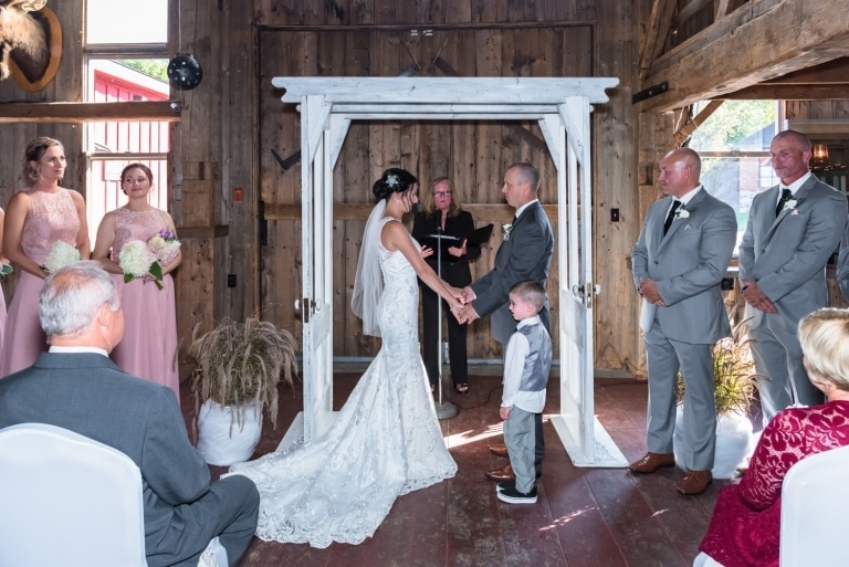 The bride and groom under the wedding arch during their wedding ceremony at the Old Orchard Inn.