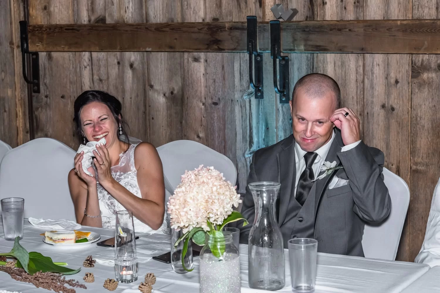 The bride and groom laughing at their wedding speeches during their wedding at the Old Orchard Inn.