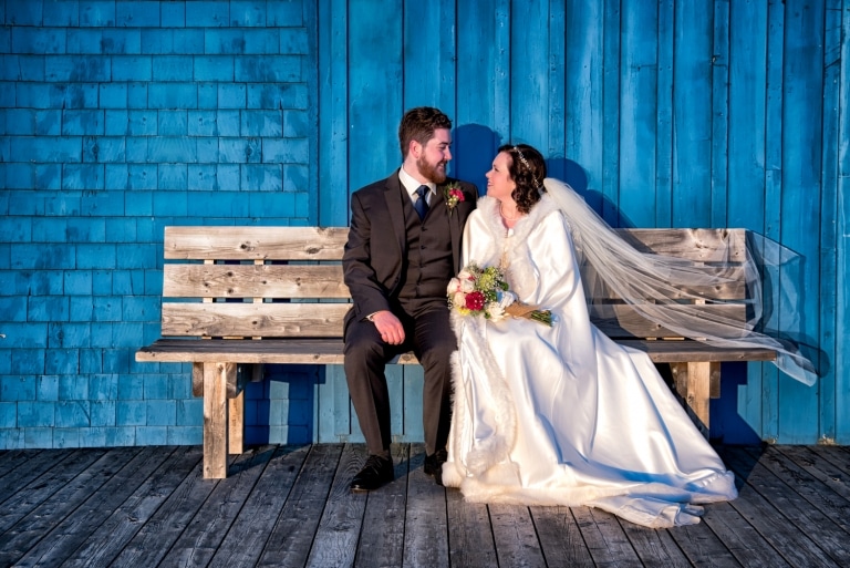 The bride and groom sitting on a wooden bench at Fishermans Cove in Eastern Passage.