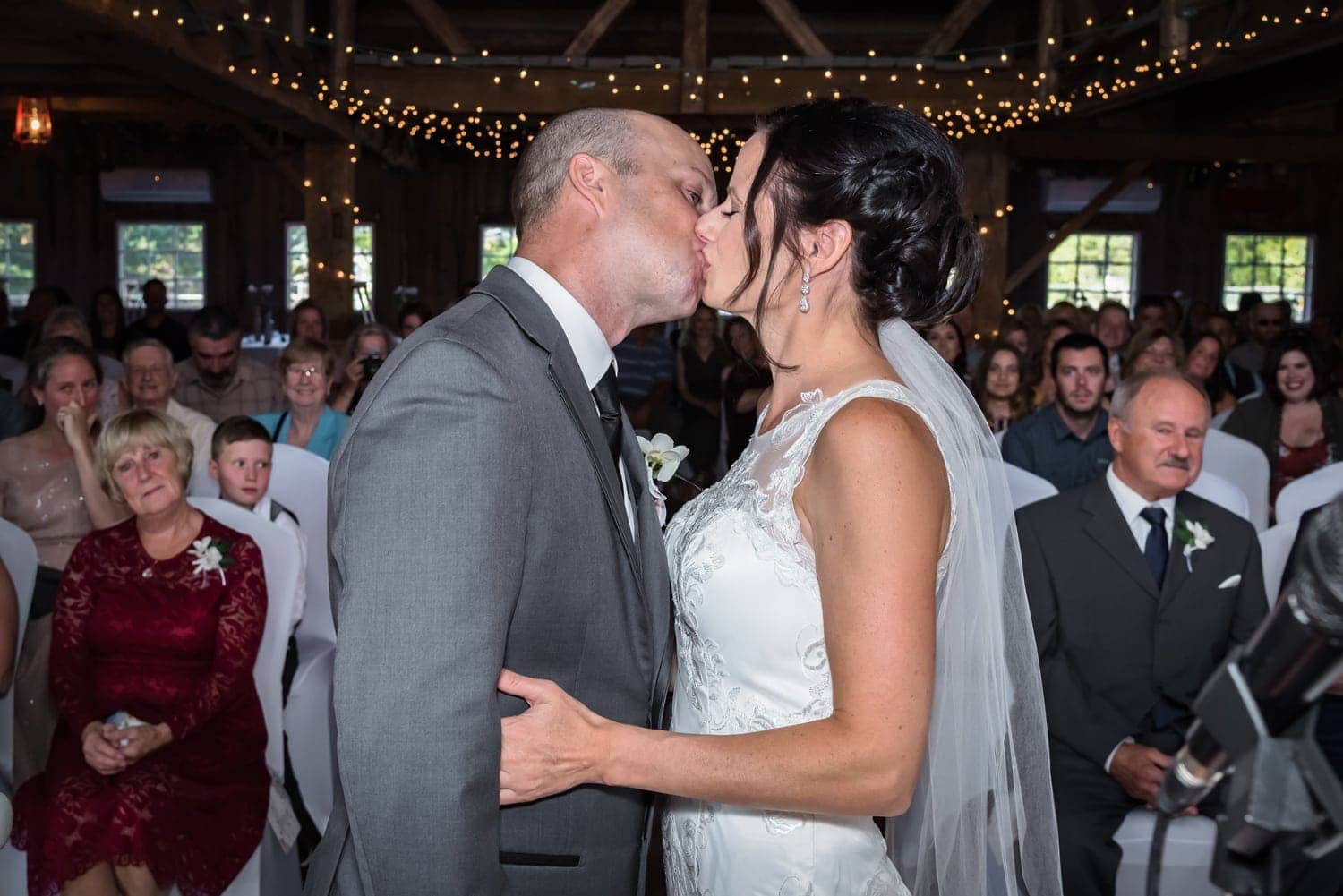 The bride and groom share a first kiss during their barn wedding ceremony in Wolfville NS.