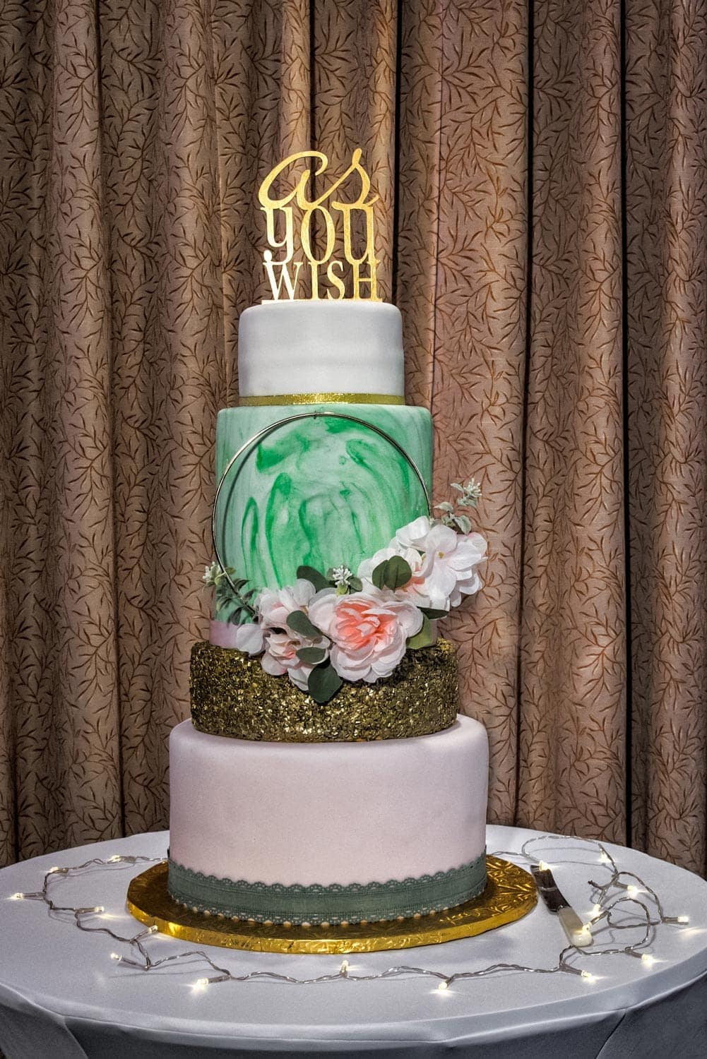 A 4 tier wedding cake with gold wedding cake topper designed by the bride at a Best Western Chocolate Lake wedding.