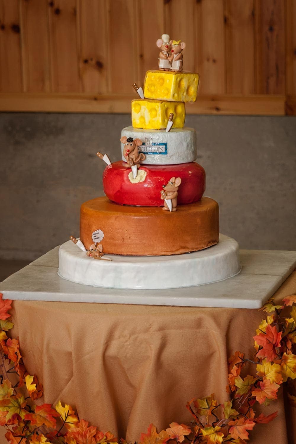 A 5 tier cheesecake themed wedding cake with mice on each level.