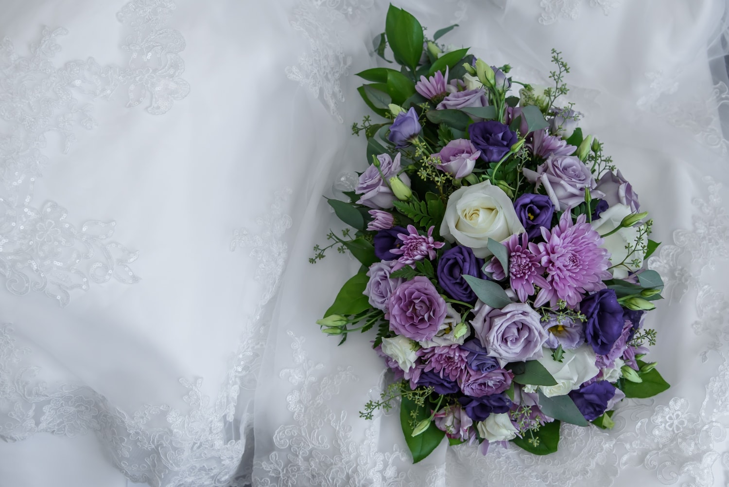 A real flower wedding bridal bouquet with ivory and purple flowers.