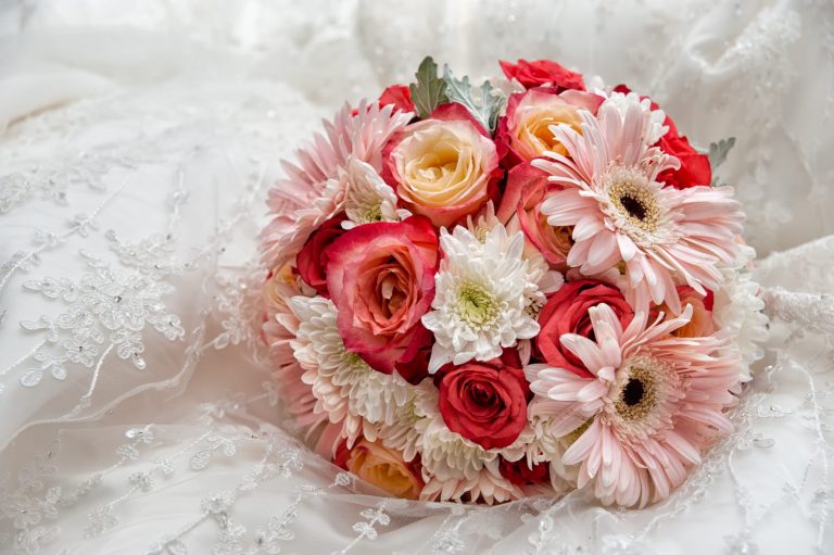 A wedding bridal bouquet with shades of pink roses and ivory flowers.