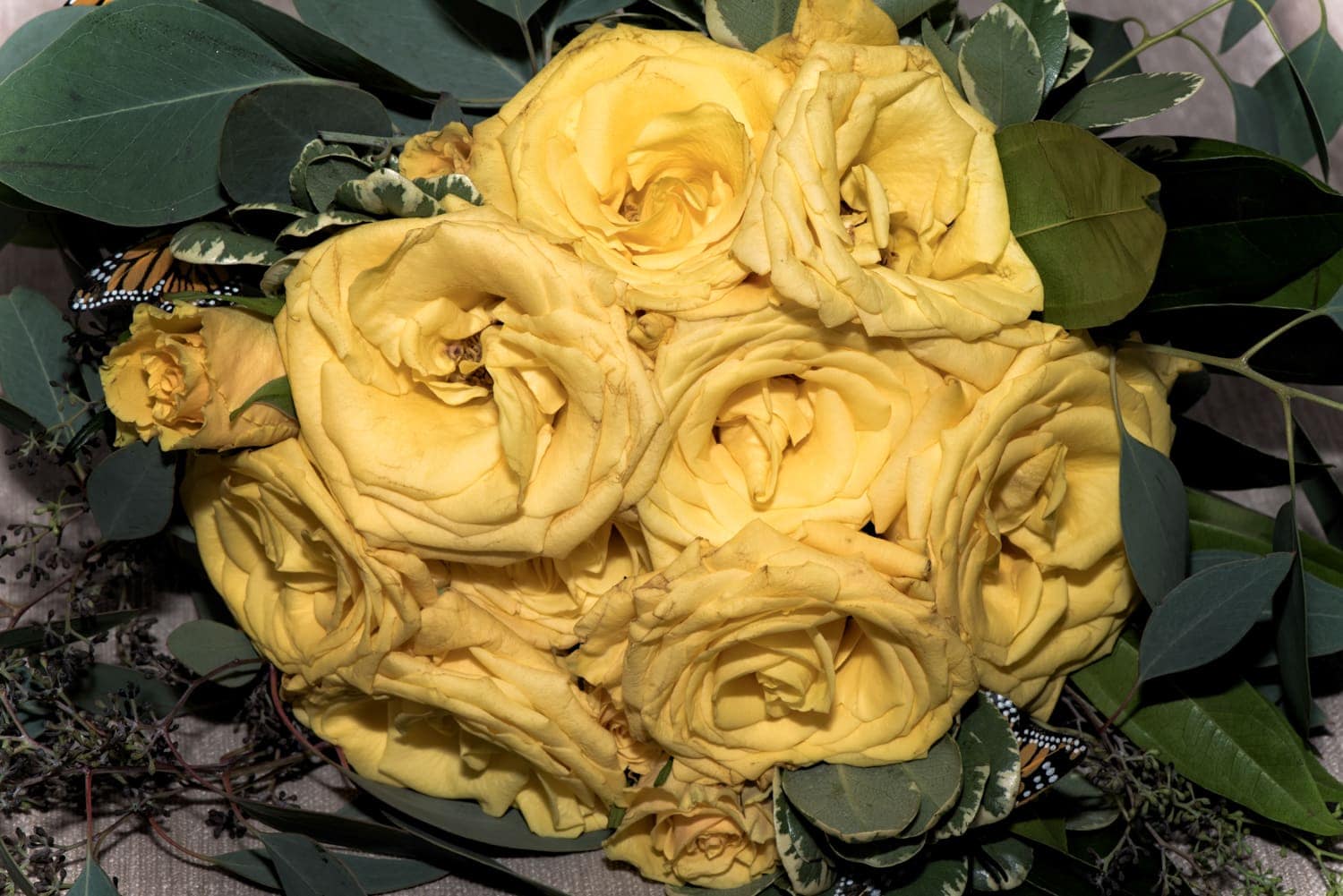 A wedding bridal bouquet with yellow roses and accented with butterflies.