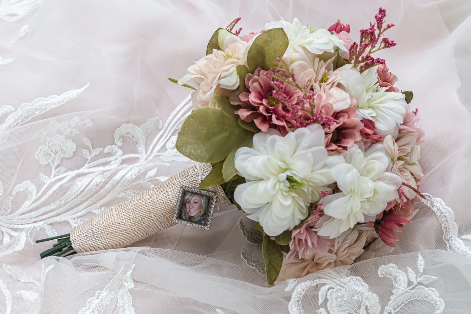 A silk flower arrangement of white, pink and green in a wedding bridal bouquet.