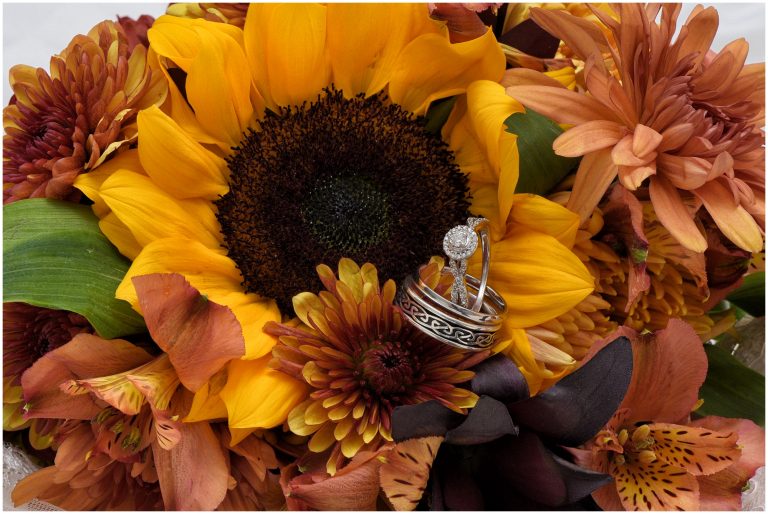 A beautiful sunflower bridal bouquet with wedding rings.