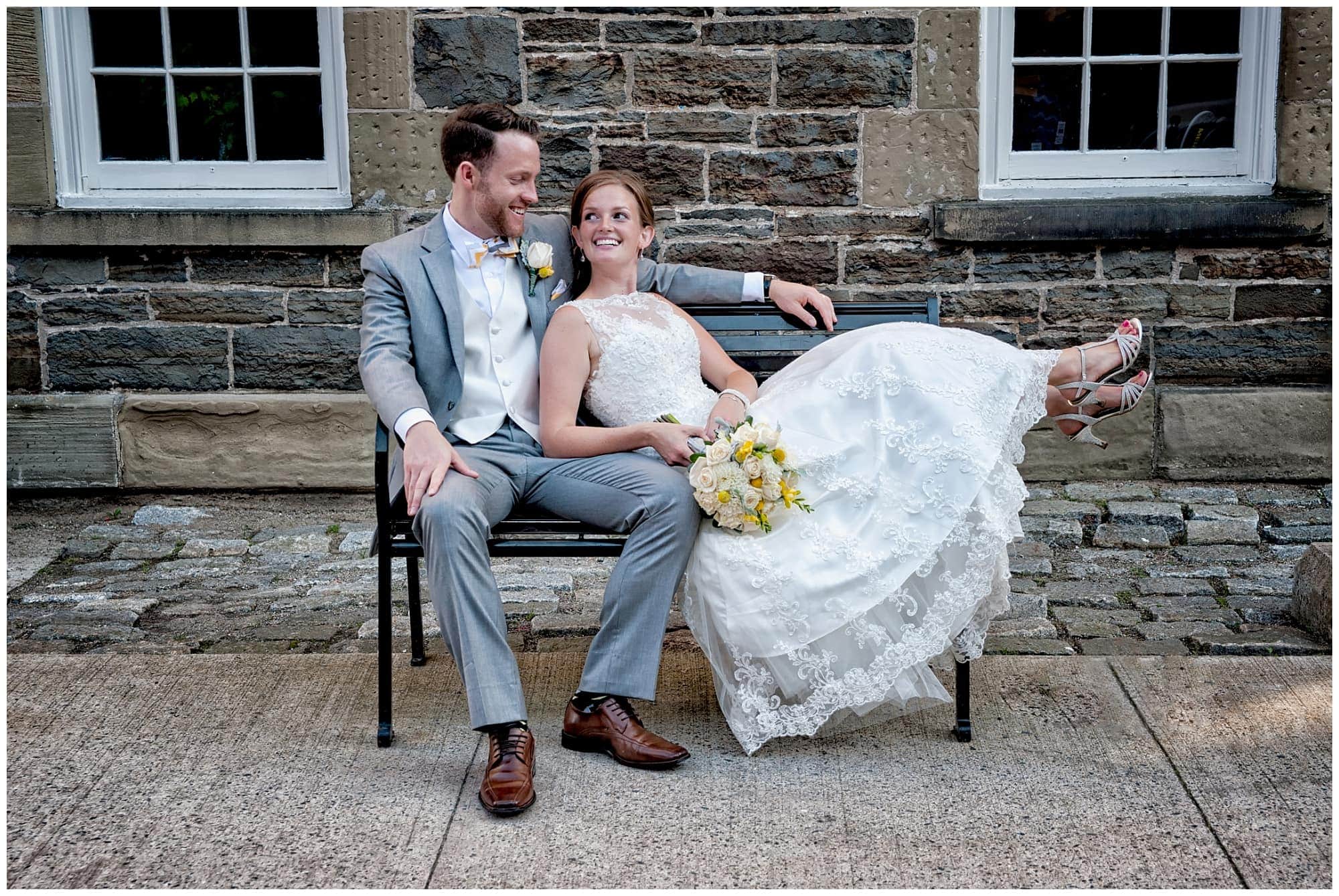 The bride and groom sitting on a rod iron bench at the Historic Properties in Halifax, NS.