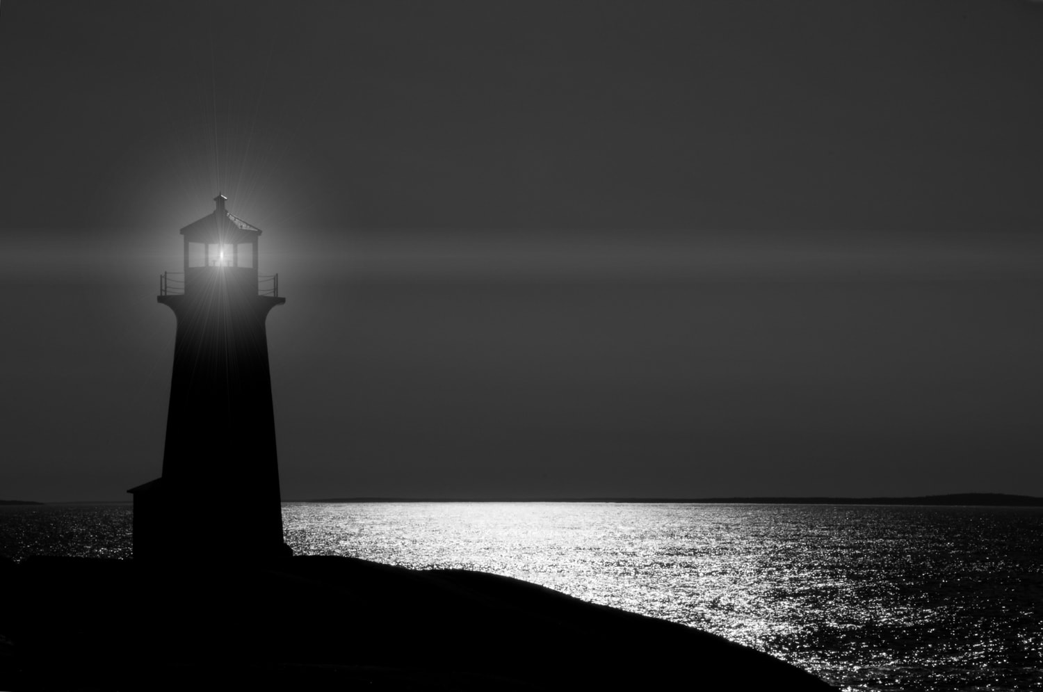 The Peggy's Cove lighthouse at night in silhouette in Nova Scotia.