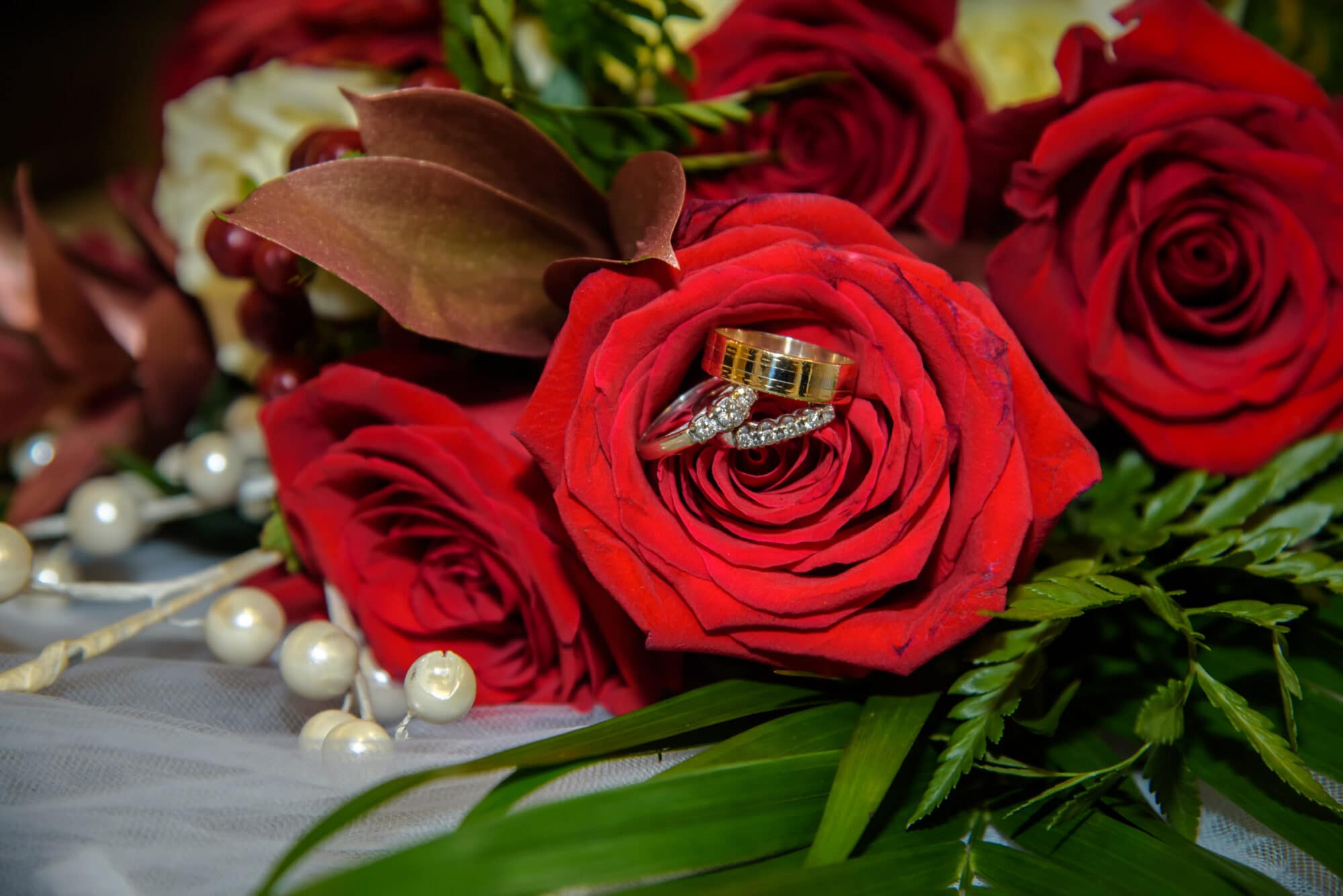 The bridal wedding bouquet of red roses with the wedding rings.