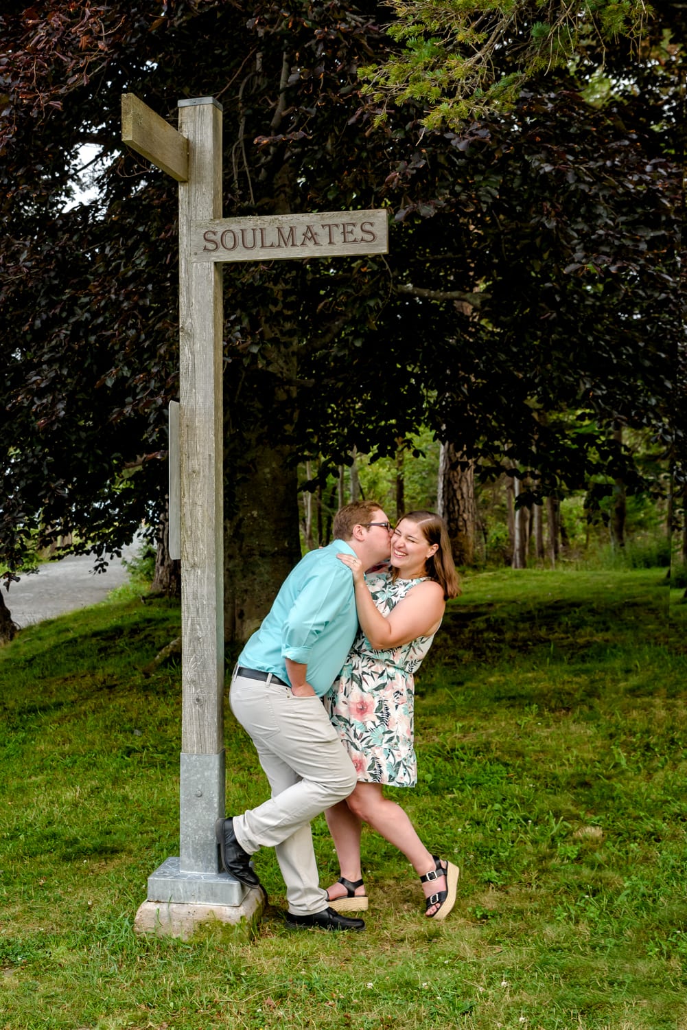 A newly engaged couple laugh and play under a soulmates street sign at the Point Pleasant Park in Halifax, NS.