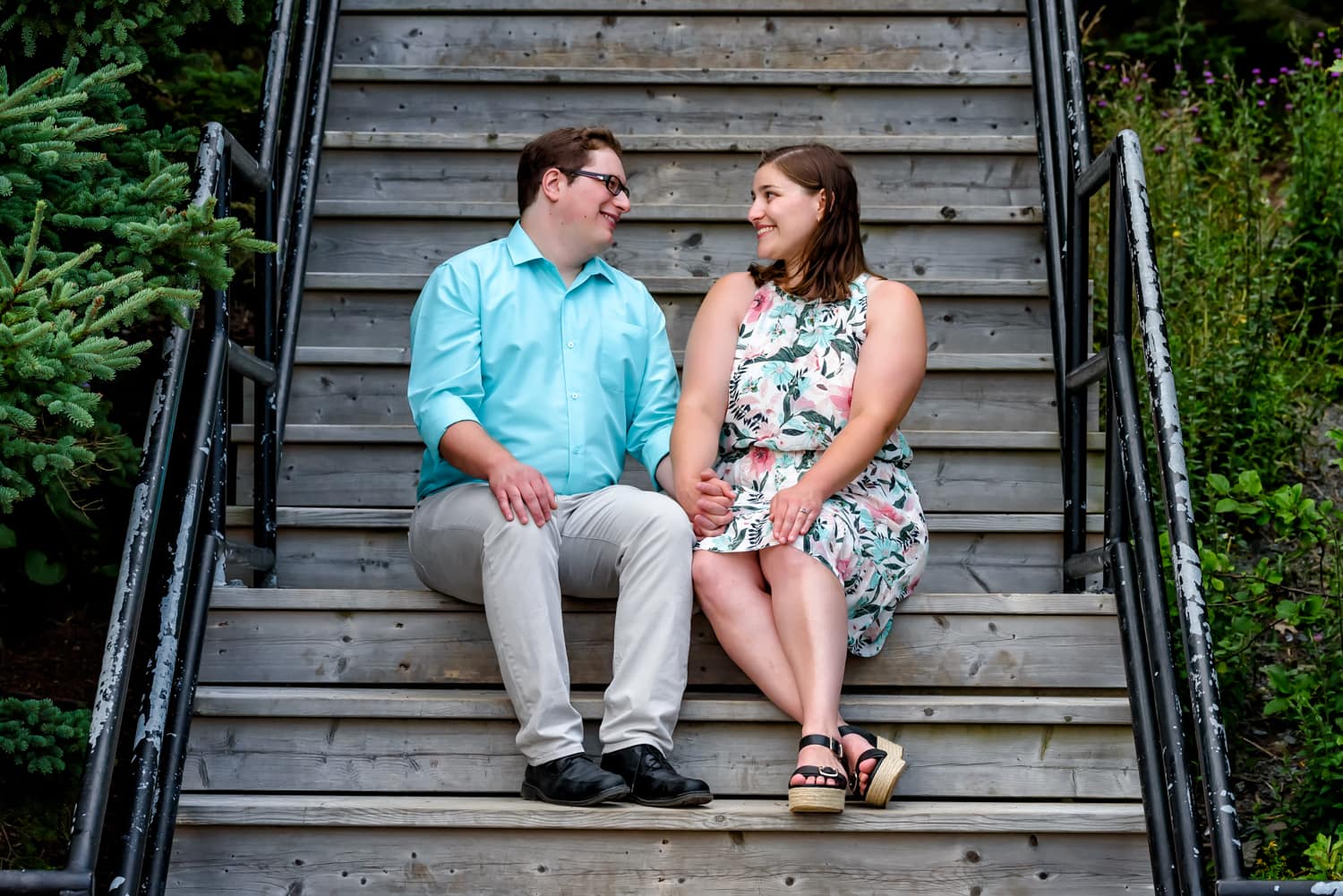 A newly engaged couple sit on wooden steps for engagement photos at Point Pleasant Park in Halifax, NS.