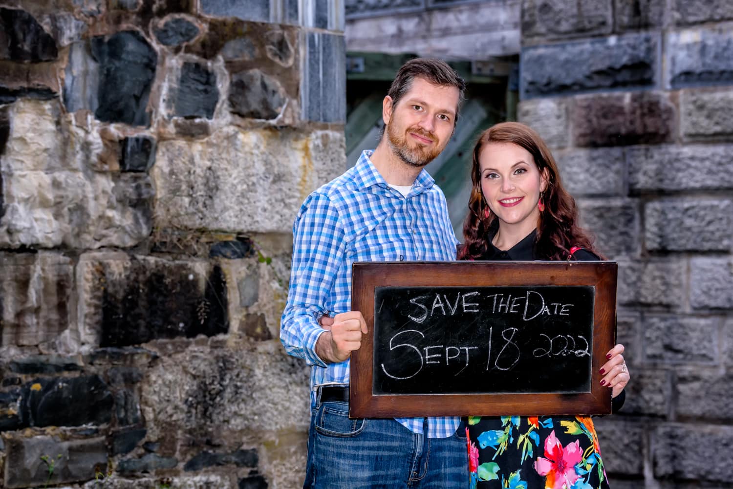 A newly engaged couple hold a save the date chalkboard sign during their engagement photos at Shubie Park in Dartmouth, NS.
