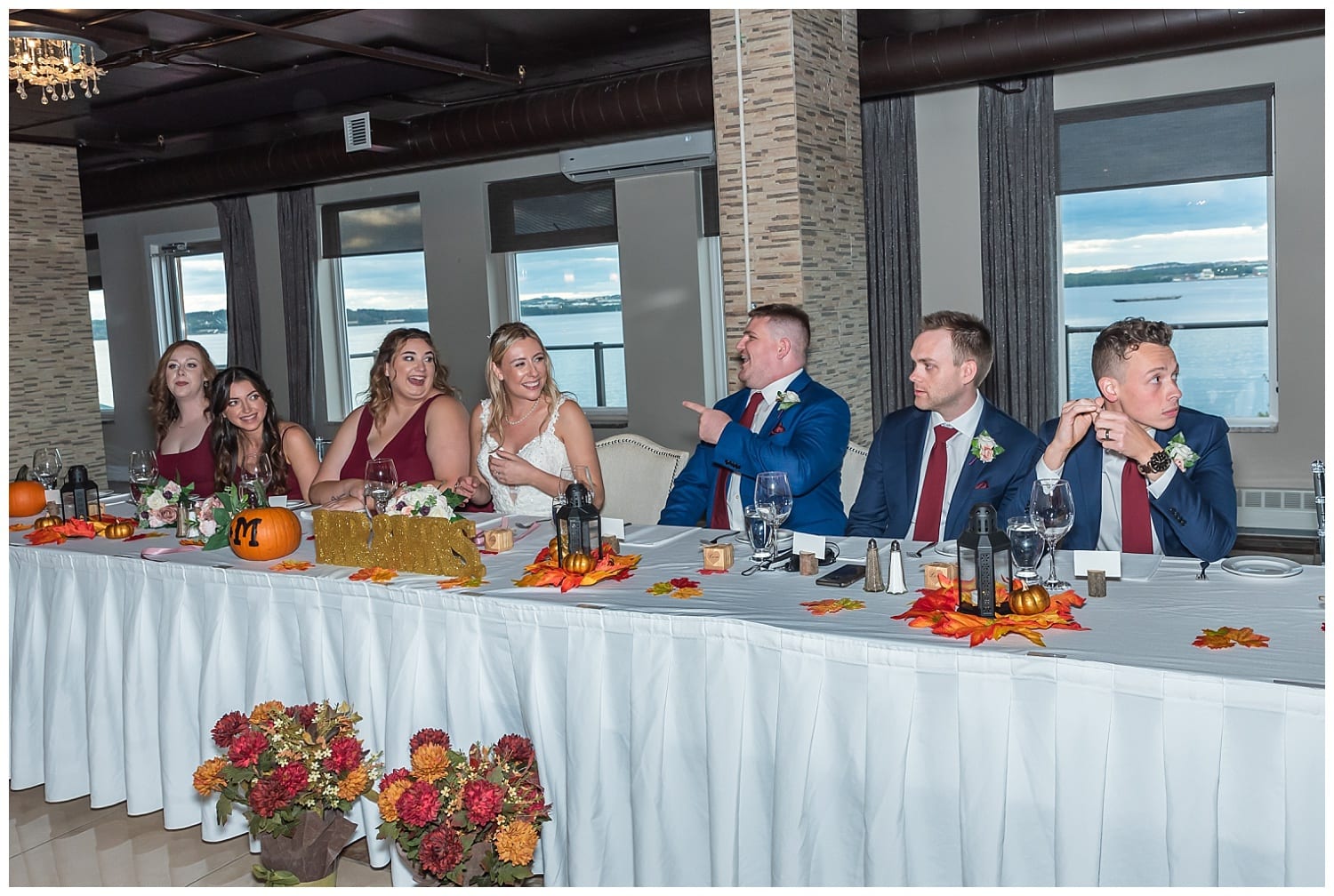 The head table with the bride, groom and wedding party during the wedding reception at Bedford Basin Farmer's Market in Halifax, NS.