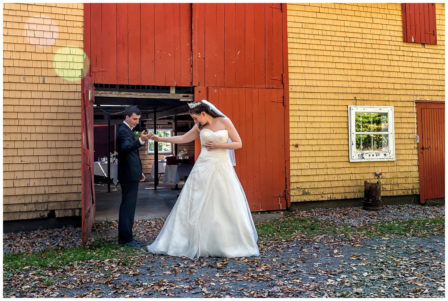 The groom eyes up the bride's gown during a rustic first look at the barn on Kinley Farm in Lunenburg NS.