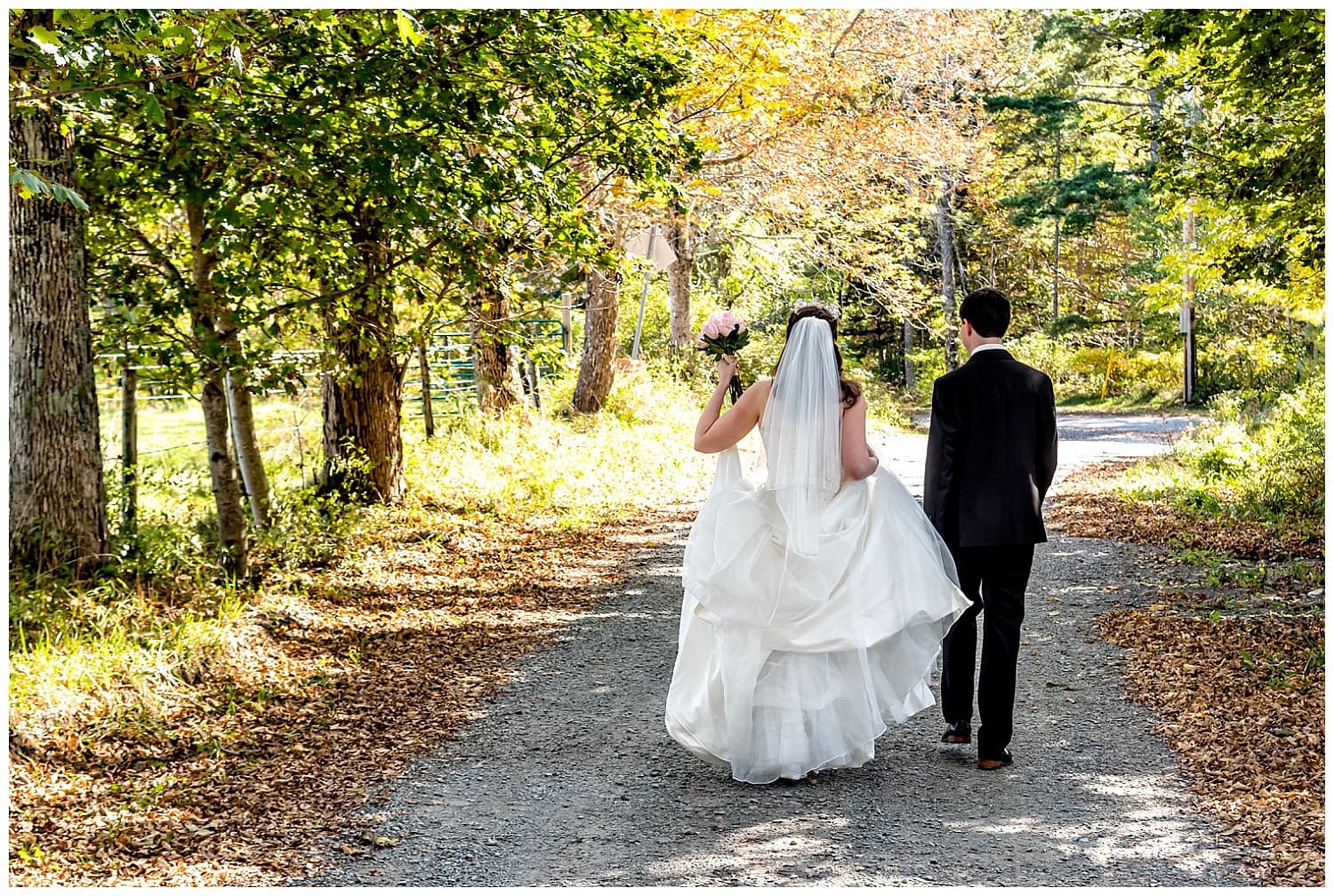 A bride and groom walk along a forest pathway on their way to their wedding ceremony at the Kinley farm in Lunenburg, NS.