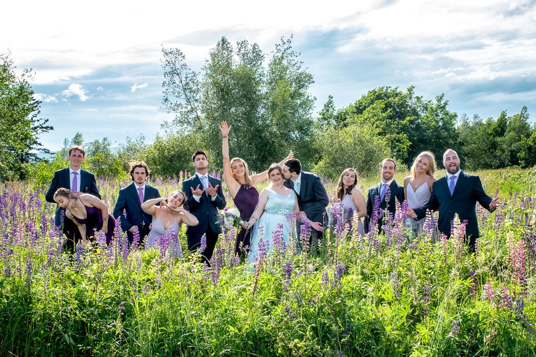 The wedding party with bride and groom having fun wedding photos taken in a lupin field in Annapolis Royal NS.