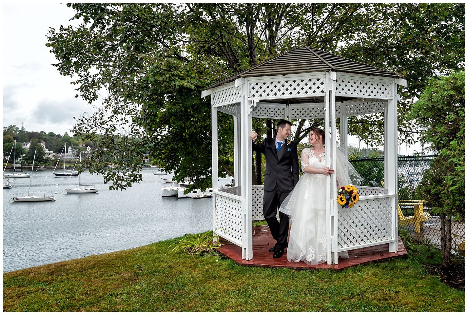 The bride and groom stand under a quaint white gazebo for wedding photos at Saraguay House.