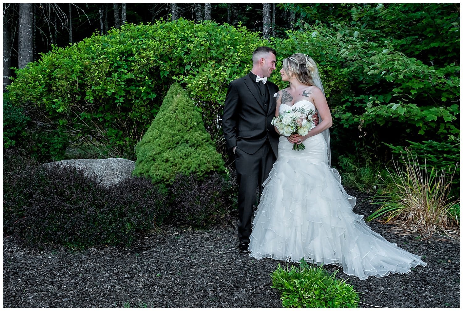 The bride and groom stand within a garden at Hatfield Farm and pose for wedding photos.