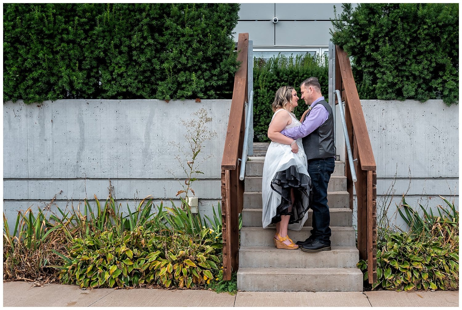 The bride and groom pose for wedding photos on steps surrounded by gardens in Dartmouth NS.