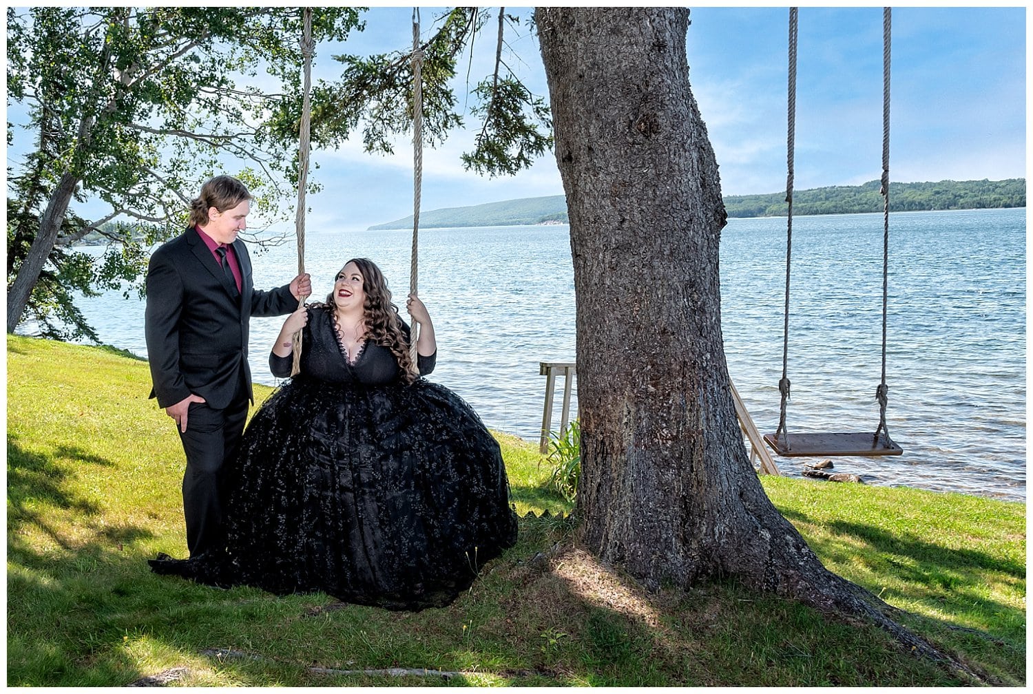 A bride sits on a swing by the ocean gazing up at her groom in Cape Breton.