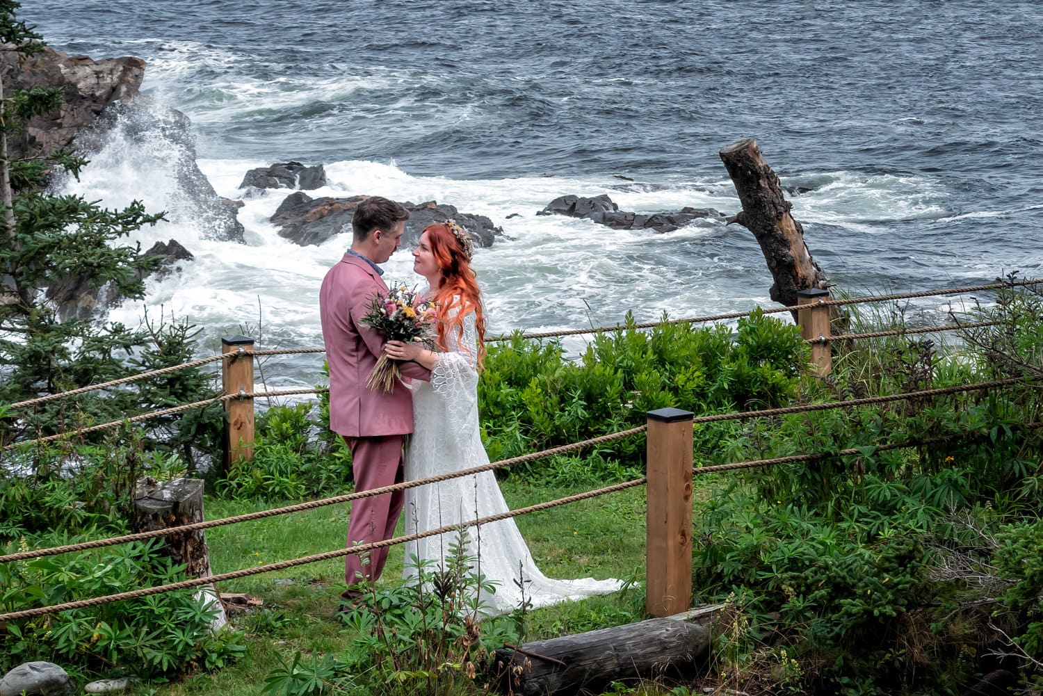 The bride and groom pose for wedding photos on the ocean in Bear Cove NS.
