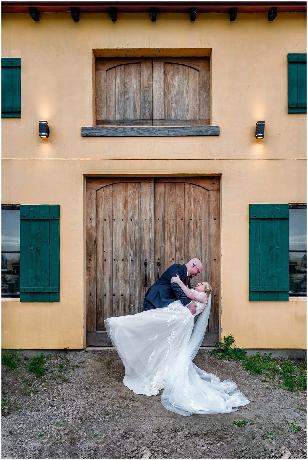 The groom dips the bride in front of a huge barn door at the Bent Ridge Winery in NS.