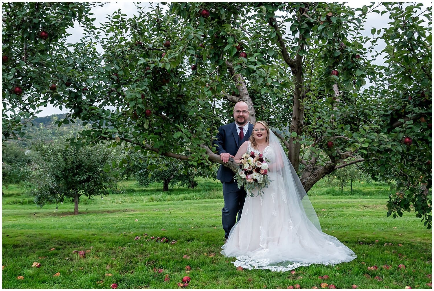 The bride and groom pose for wedding photos in an apple orchard at Bent Ridge Winery in NS.