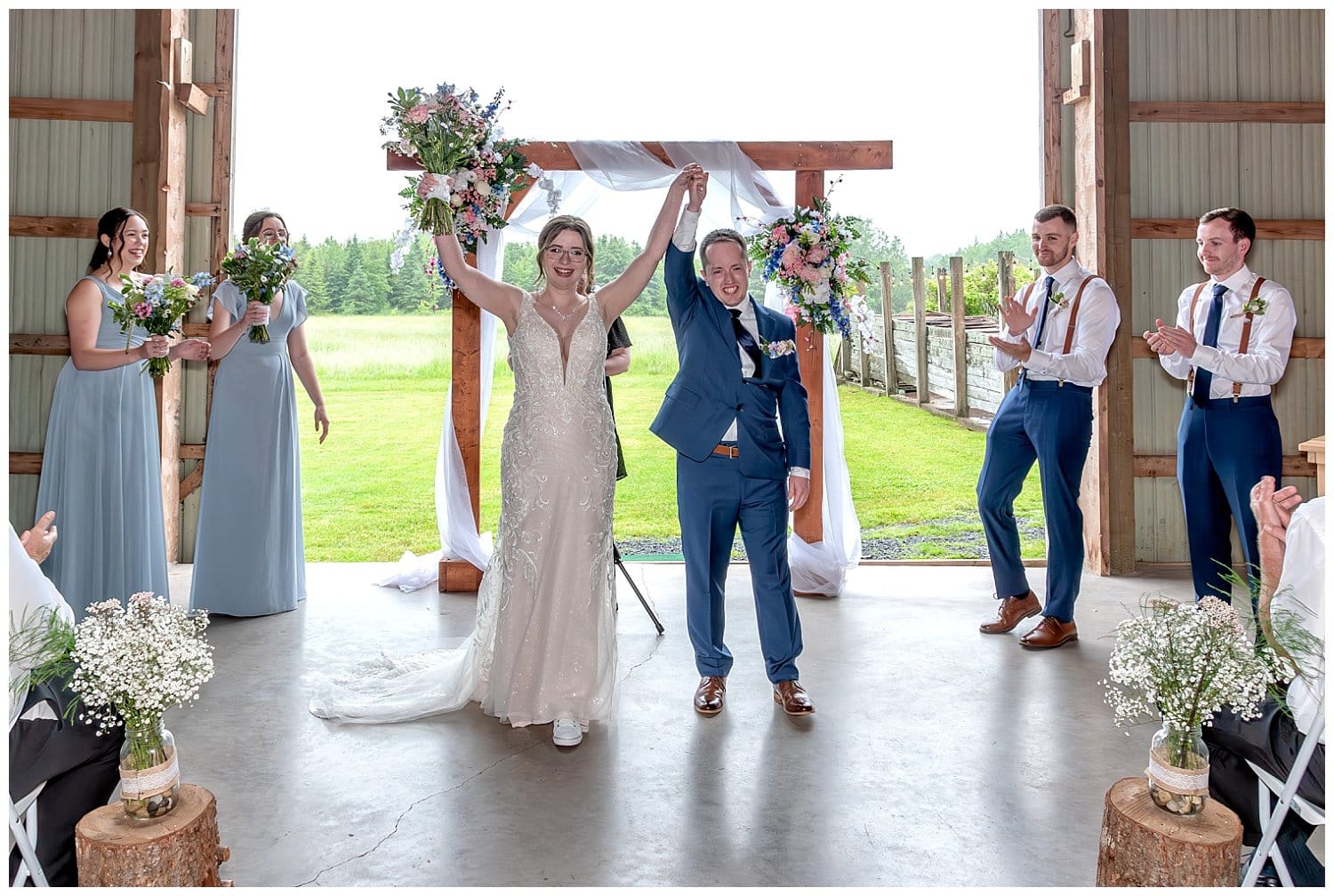 The bride and groom raise their arms after their wedding ceremony at Parkers Barn in Hopewell NS.