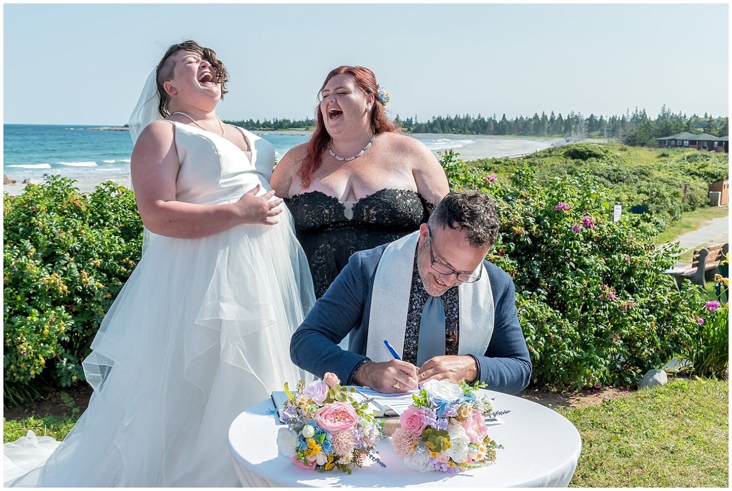 The brides laugh together during the signing of their marriage certificate at White Point Resort in NS.