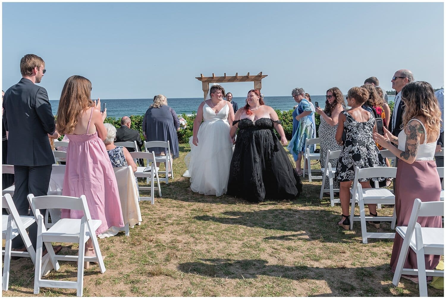 Both brides walk down the aisle during their LGBT wedding ceremony at White Point Beach Resort NS.