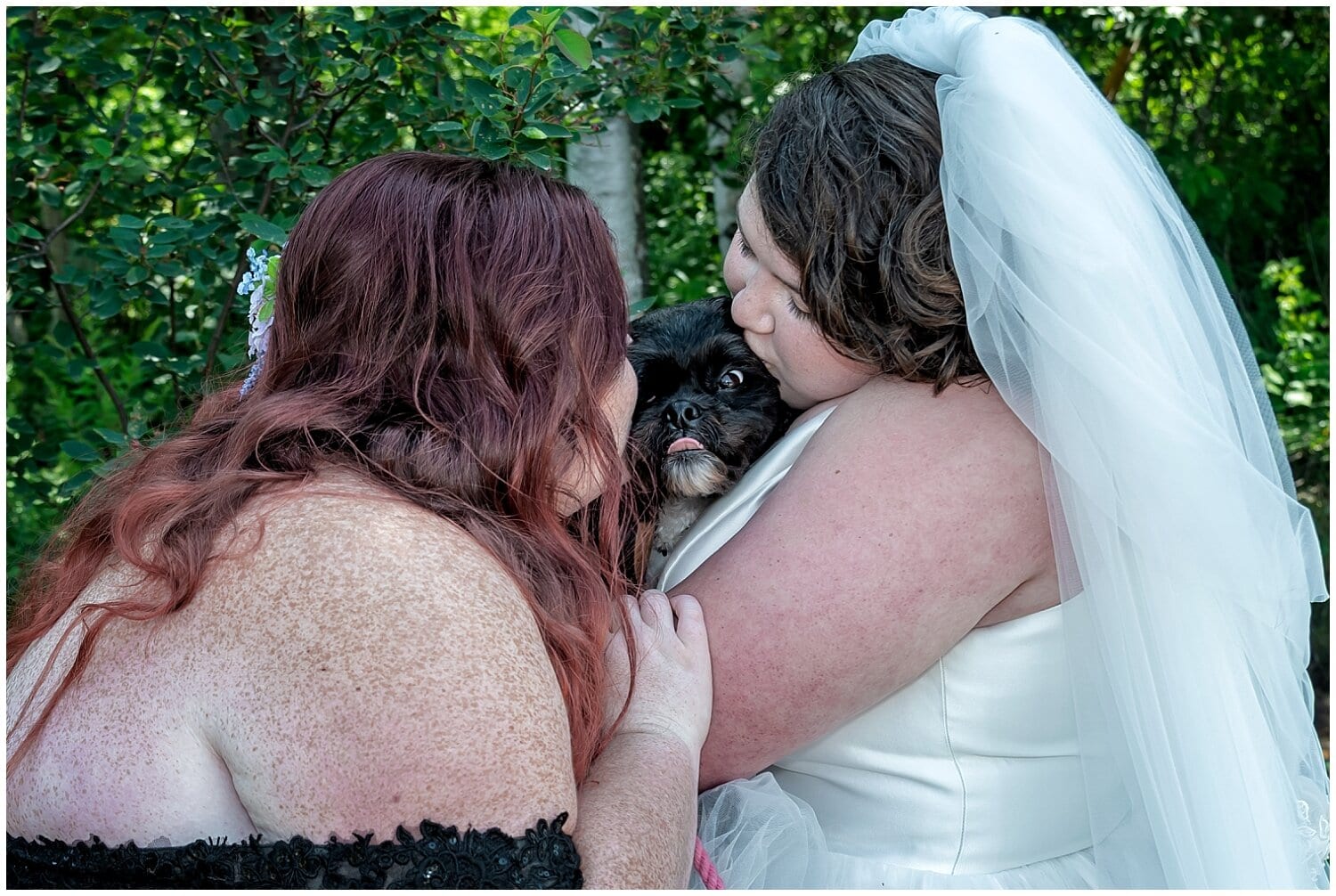 The brides kiss their dog Onyx who was the flower dog at their wedding at White Point Resort in NS.