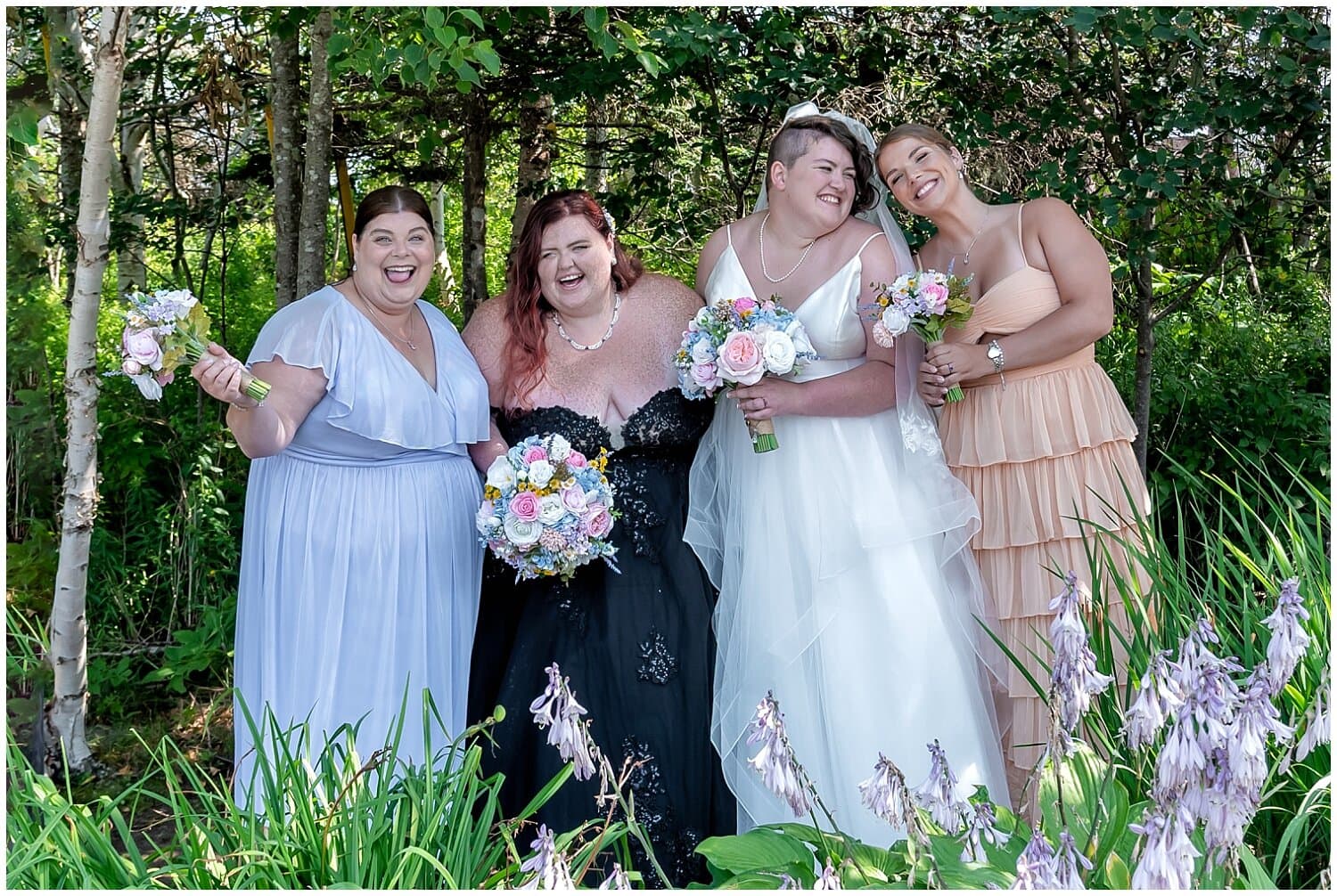 The brides pose for wedding photos with their bridesmaids during their wedding at White Point Resort in NS.