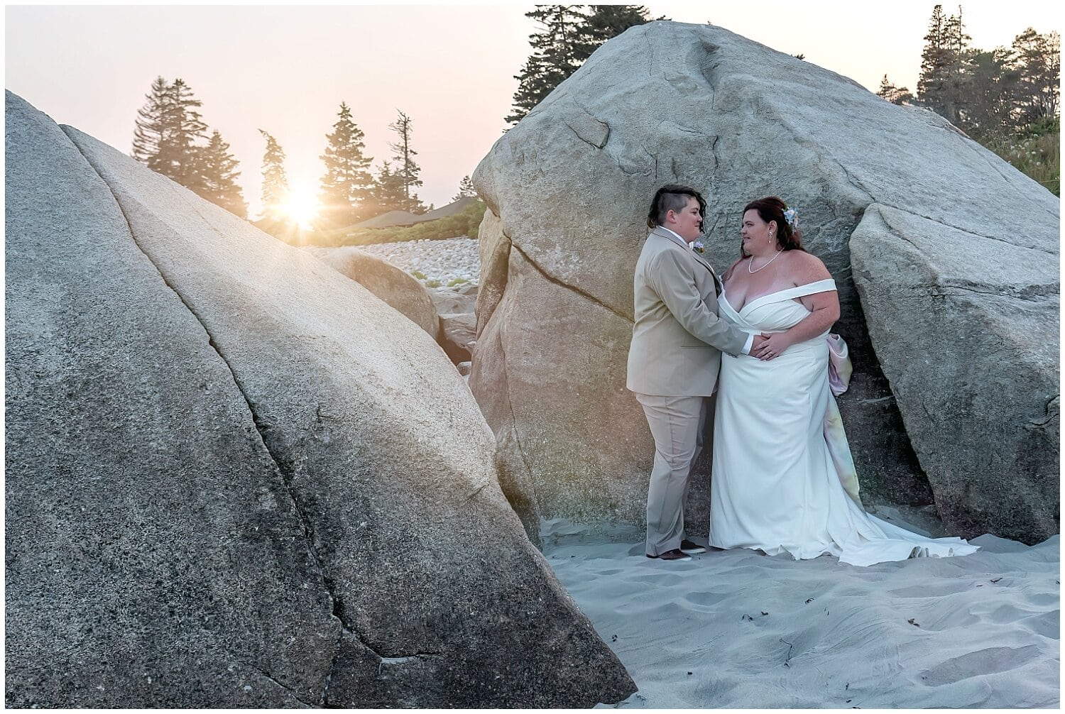 The brides pose for wedding photos on the beach after a wardrobe change during their wedding at White Point Resort in NS.