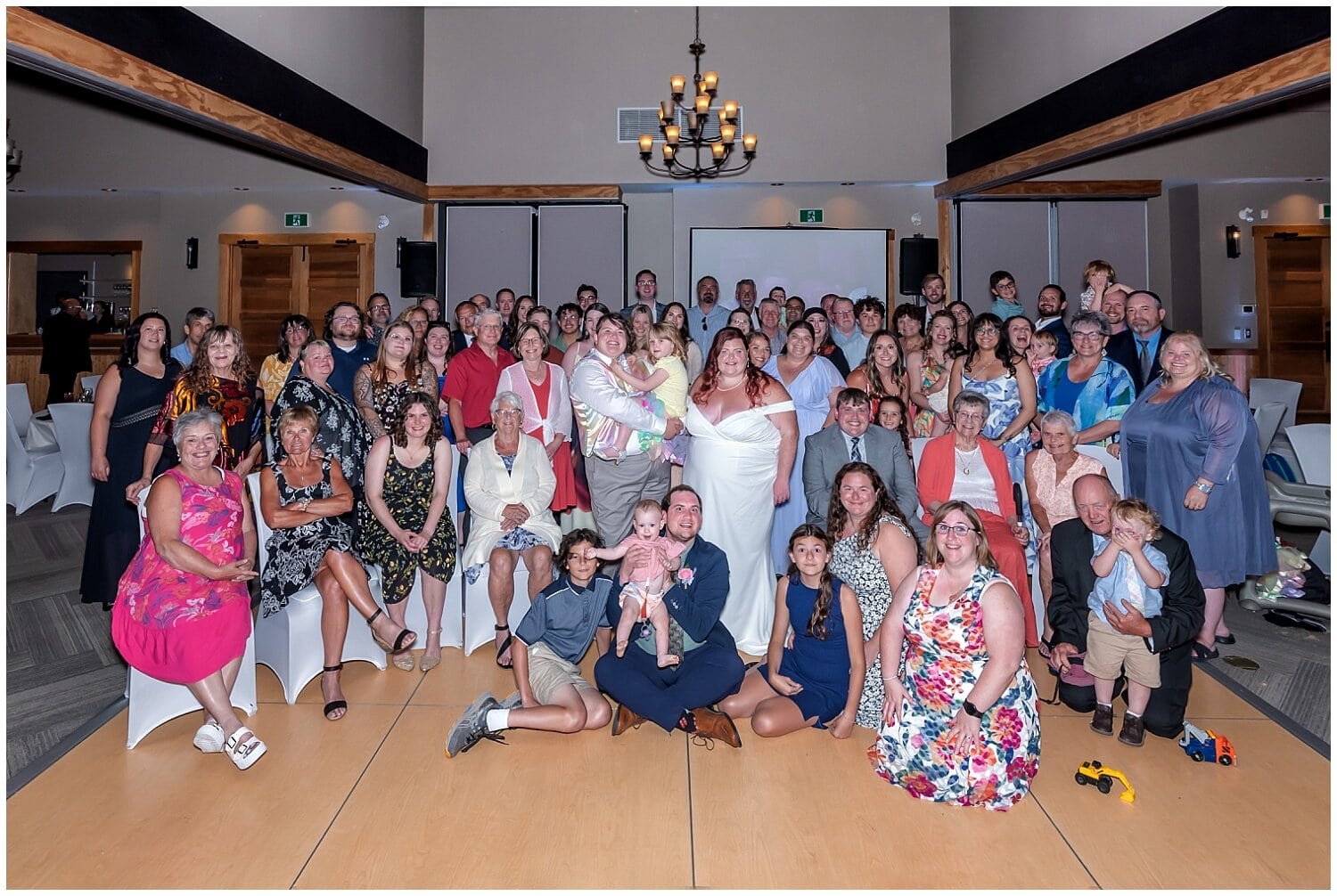 The brides pose for a huge image with all their guests and bridal party during their wedding reception at White Point Beach Resort in NS.