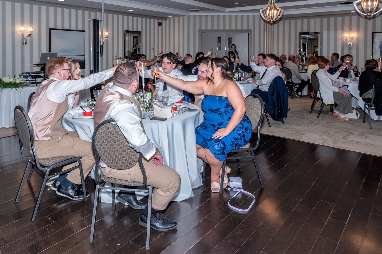 Wedding guests raising glasses in a celebratory toast during the reception at Ashburn Golf Club.