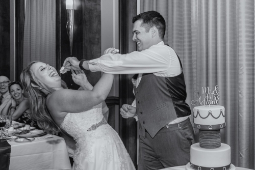A bride and groom smush wedding cake into each other's face during a Juno Tower wedding.