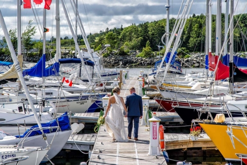 A bride and groom walking among the boats at the Dartmouth Yacht Club for wedding photos.