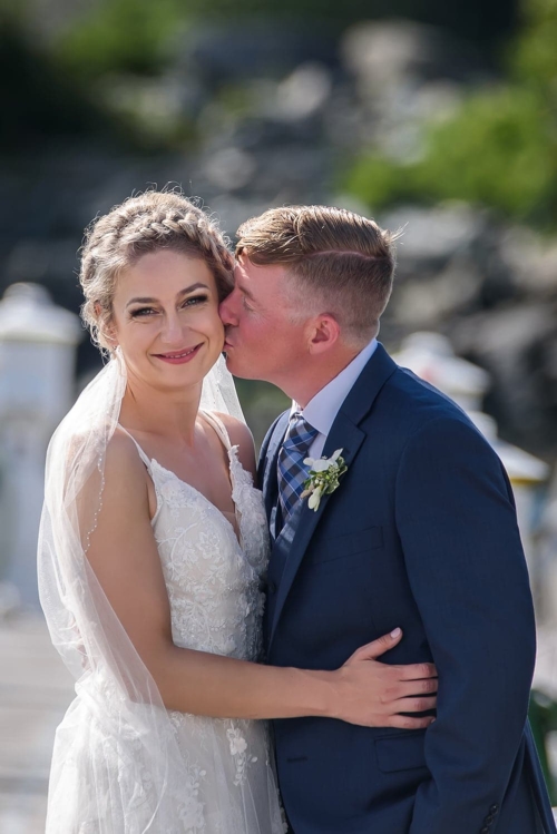 A groom giving his bride a kiss during wedding photos at the Dartmouth Yacht Club.