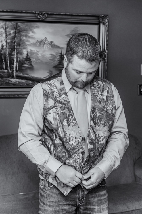 A groom putting on a camouflage vest for his wedding in Truro NS.
