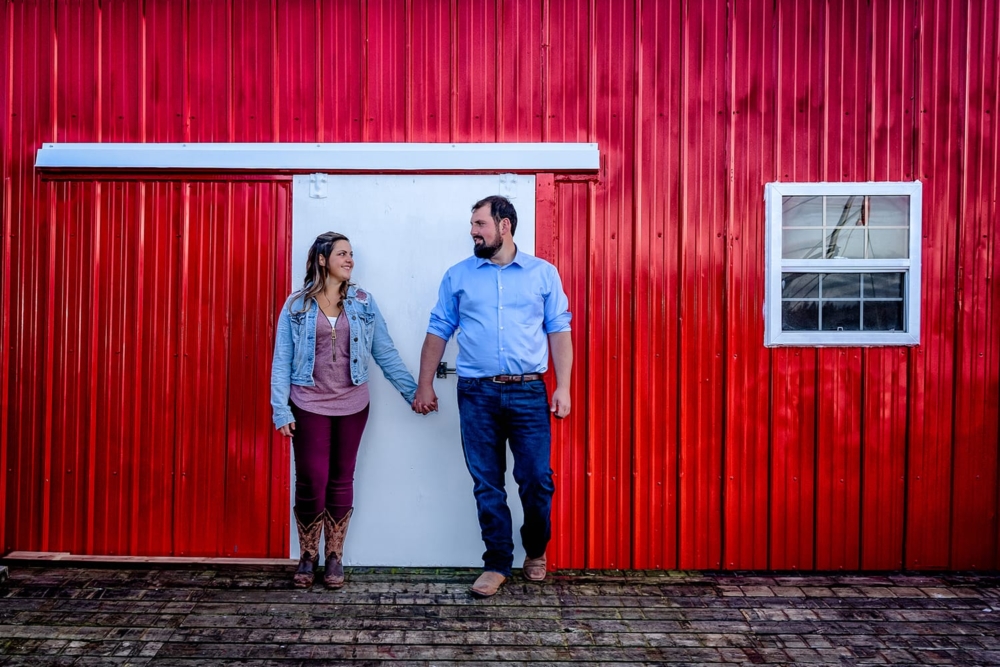 A loving couple stand hand in hand infront of their red fishing shack at Peggys Cove, NS.