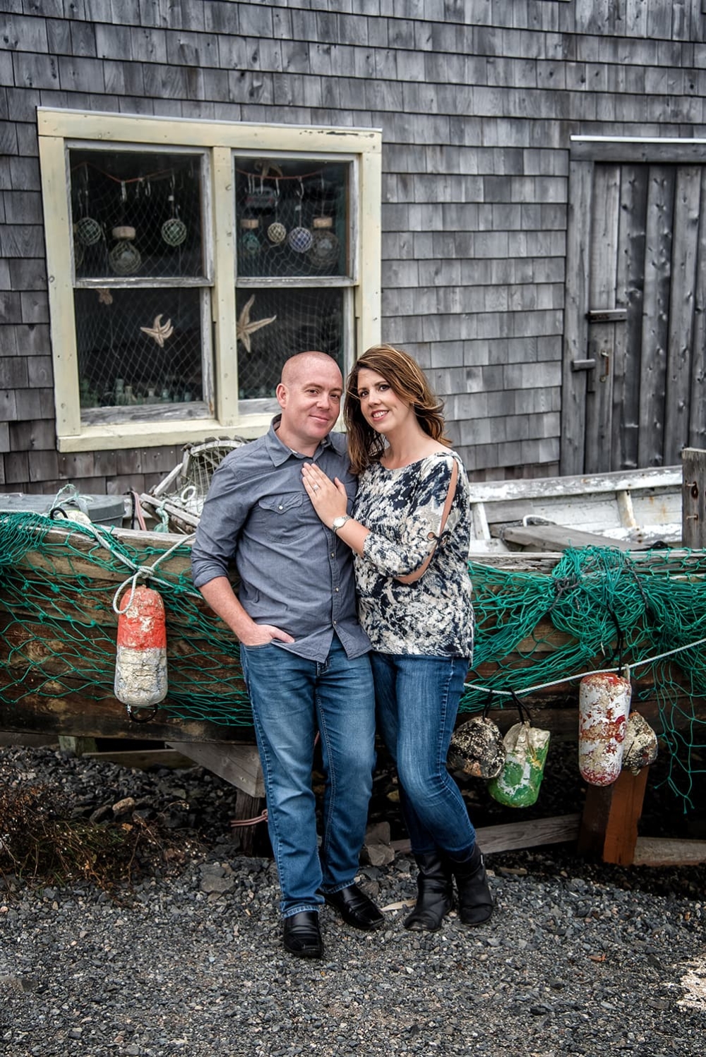 Engagement photos of a couple in love standing infront of a fishing boat at Peggys Cove, NS.