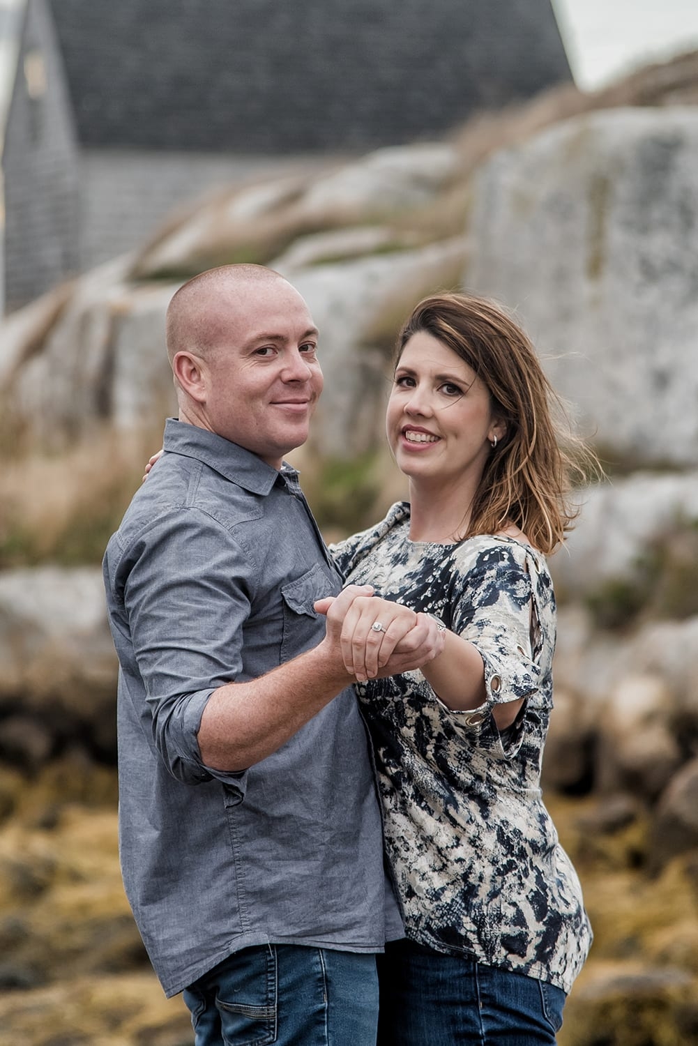 A couple in love holding hands, engagement photos at Peggys Cove, NS.