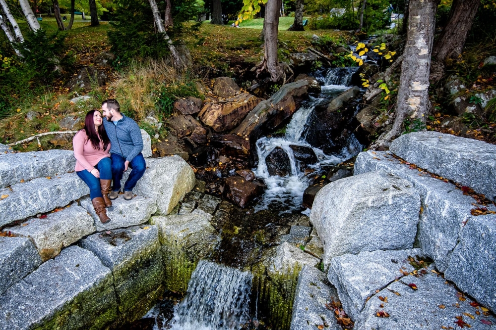 A couple in love holding each other by a waterfall during engagement photos at Dingle Park in Halifax, NS