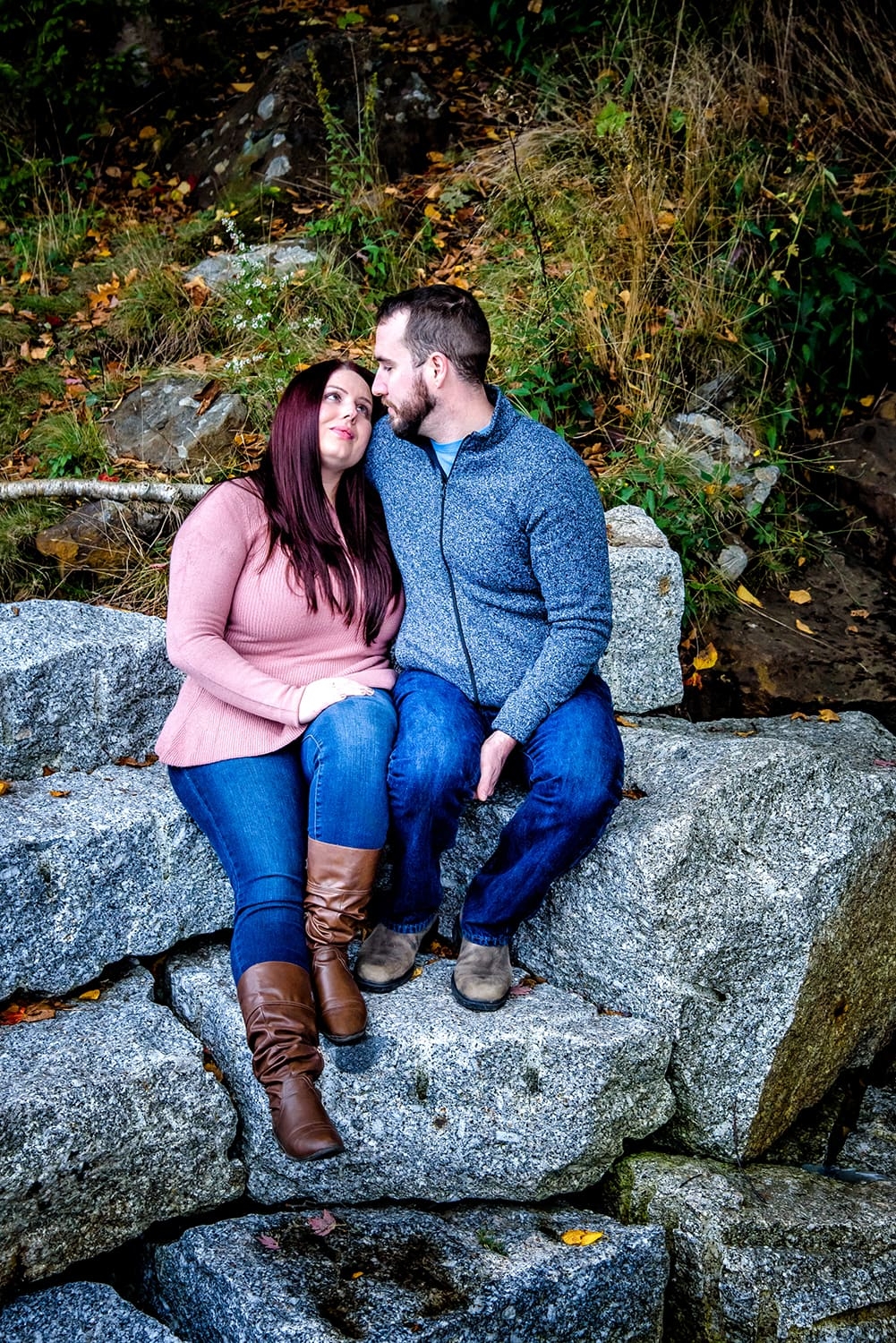 A young couple holding each other by a waterfall during engagement photos at Dingle Park in Halifax, NS.