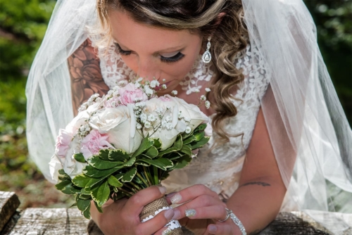 A bride in a candid moment smelling her rose floral bridal bouquet.
