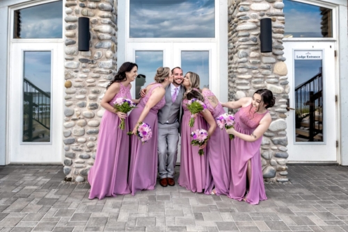 The groom being kissed by the bridesmaids at a wedding at White Point in Nova Scotia.
